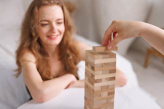 two women playing Jenga board game at home, excitement and relaxation, mind development concept,