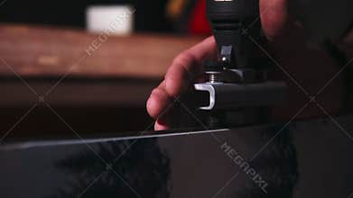 Close-up image of a man sharping ski edges with sharpening tool at the workshop holding skies in vice