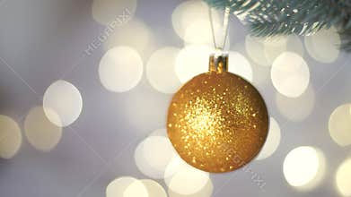 Golden Christmas Ball on Christmas Tree with light bokeh on background. New Year's festive Christmas balls