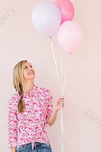 Woman Looking Up At Balloons Against Pink Background