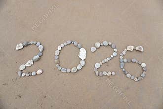 The stones arranged neatly on the beach form the number 2026
