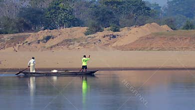 Two fishermen on a wooden boat in a calm river during daytime