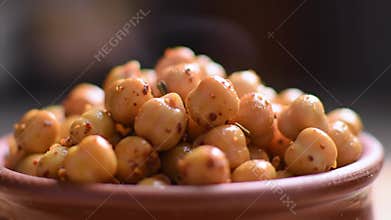 Close-up view of a bowl filled with seasoned chickpeas, showcasing their golden color and textured surface, perfect for food-