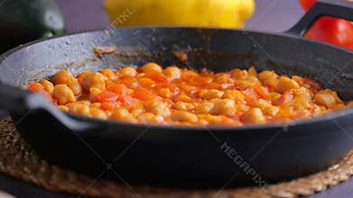 Cooking chickpeas with tomatoes in a black pot