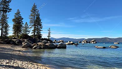 Wide scenic view of Sand Harbor beach cove with emerald water and pine forest background