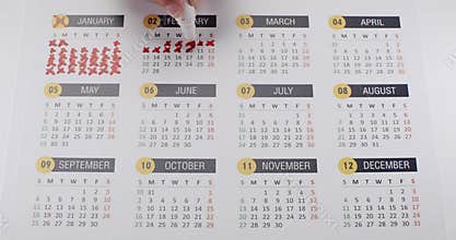 Person Marking Days on a Calendar with Red Pen Highlighting Important Dates