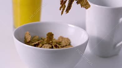 Cereal pouring into a bowl at breakfast table