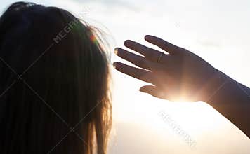 Woman hiding from the sun with hand