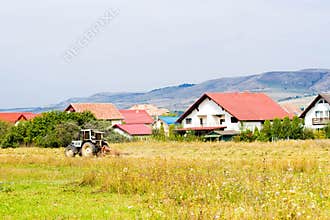 Rural summer landscape with tractor and cottages