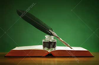 Quill pen and inkwell on old book