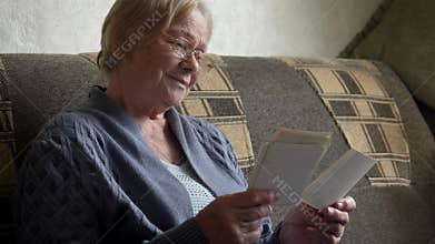 Elderly woman browsing vintage old black white photos reminiscing about past
