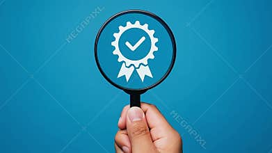 Hand holding magnifying glass focus on quality certified icon over blue background