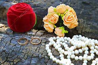 Wedding rings, boutonniere and a string of pearls