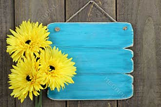 Blank antique blue sign with large yellow sunflowers hanging on rustic wood fence
