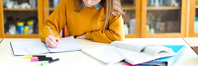 Young female college student in chemistry class, writing notes. Focused student in classroom.
