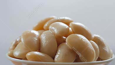 A portion of boiled white large beans rotates in the frame