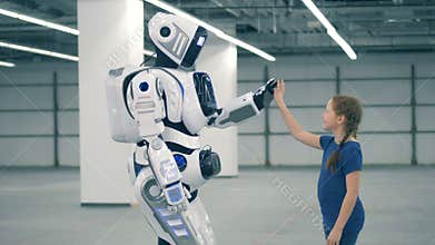 High-five gesture of a little girl and a robotic humanoid