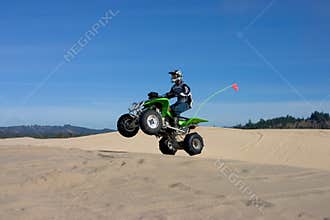 Man jumping ATV in sand dunes