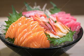 Mixed sliced fish sashimi on ice in black bowl. Sashimi Salmon Tuna Hamachi Prawn and Surf Calm set, raw fish, japanese food in