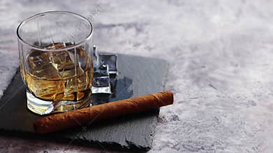 Glass of whiskey with ice cubes and cigar