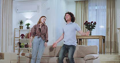 Moving day for a young attractive couple they carrying the big sofa in the living the very excited falling down on the