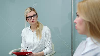 Psychologist is attentively listening client woman talking about her problems at therapy.
