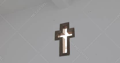 Catholic cross in church wall, light going through
