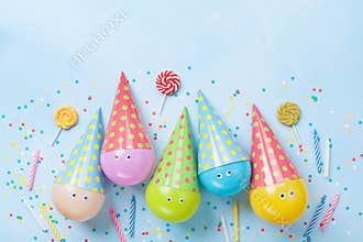 Birthday or party background. Funny balloons, candy and confetti on blue table top view. Flat lay. Invitation card.