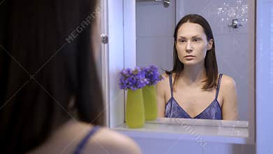 Reflection of unhappy pretty woman in mirror