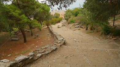 Ancient stony road through park to modern city, decaying old infrastructure