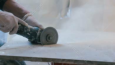 Worker cutting a tile using an angle grinder at construction site