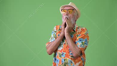 Handsome senior bearded tourist man ready for vacation against green background