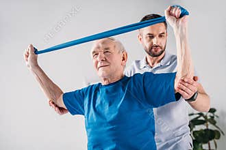 focused rehabilitation therapist assisting senior man