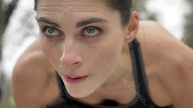 Young motivated girl is preparing to run in park in summer, heathy lifestyle, sport conception