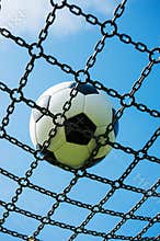 Soccer ball in chain net white and black football, blue sky