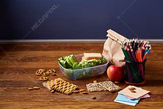 Back to School concept, school supplies, biscuits and lunchbox on wooden desk, selective focus, close-up.