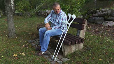 Tired disabled man massages the aching leg