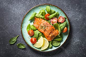 Baked salmon fish fillet with fresh salad top view.