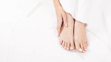 Female feet on towel. Nails getting a fresh and accurate look during a pedicure procedure.