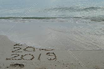 Happy New Years 2017, 2018 and 2019 handwritten on sand