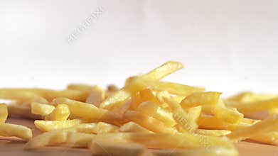 Close up slow motion fried potato chips falling down from top to wooden table