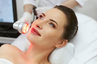Red Led Light Treatment. Woman Doing Facial Skin Therapy