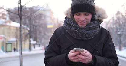 Man walking and using mobile phone on a cold winter day