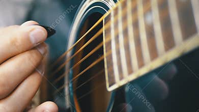 Man playing an acoustic guitar with a mediator. Slow motion