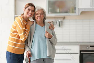 Elderly woman with female caregiver in kitchen.
