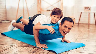 Boy Liying Fathers Back on Mat Doing Push Ups
