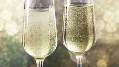 Filling flutes of champagne with golden bubbles against gold bokeh background, concept of golden luxury holiday happy new year