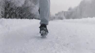 Silhouette of a man running along a snowy road in winter in a park