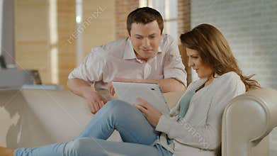 Happy young couple watching family photos on tablet PC, memories