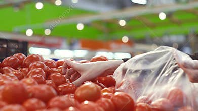 Women`s hands choose fresh juicy tomatoes in the supermarket